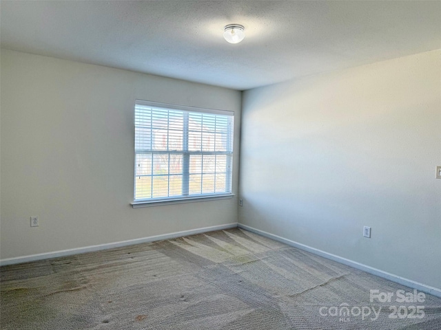 carpeted empty room featuring baseboards