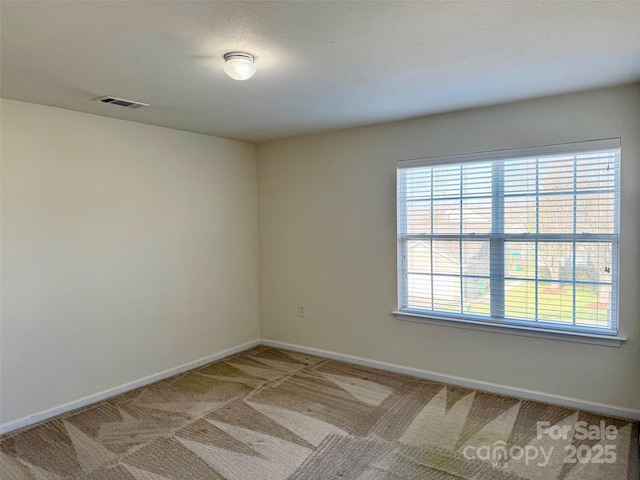 unfurnished room with baseboards, visible vents, and light colored carpet