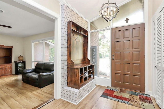 entryway featuring light hardwood / wood-style flooring, ornamental molding, and a chandelier