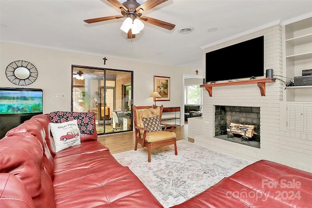 living room with crown molding, light hardwood / wood-style flooring, a fireplace, and ceiling fan