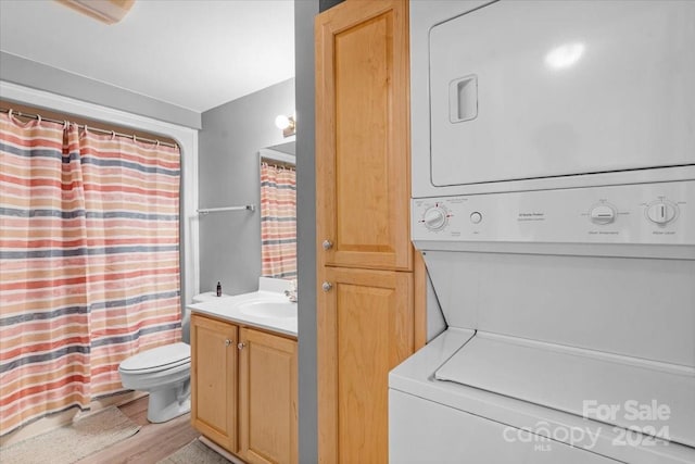 laundry area featuring sink, stacked washing maching and dryer, and light hardwood / wood-style flooring