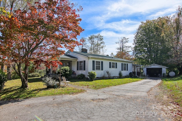 view of front of house with a front yard, a garage, and an outbuilding