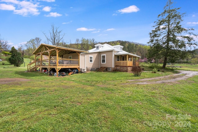 rear view of house featuring a wooden deck and a lawn