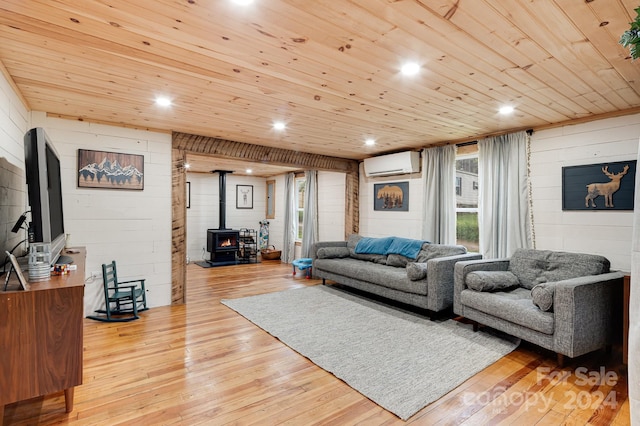 living room featuring light wood-type flooring, wooden ceiling, a wood stove, and a wall unit AC