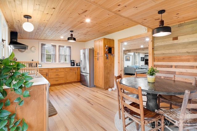 kitchen featuring pendant lighting, light wood-type flooring, stainless steel fridge, and exhaust hood