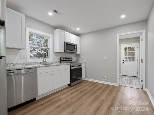 kitchen featuring appliances with stainless steel finishes, sink, a wealth of natural light, and white cabinets