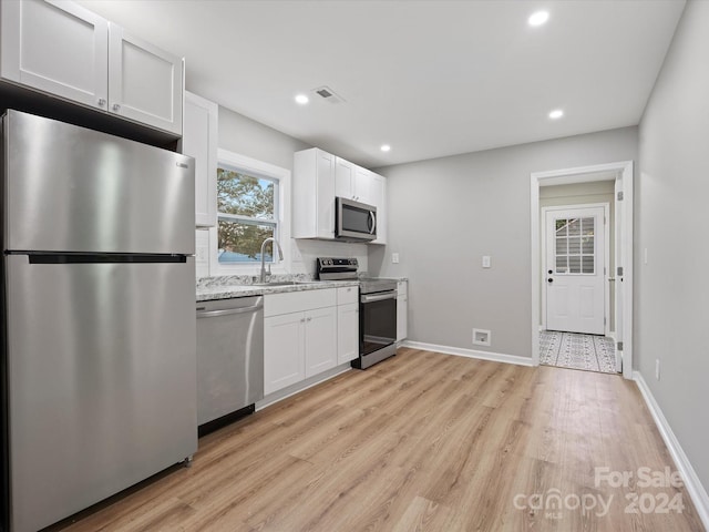 kitchen with white cabinetry, light hardwood / wood-style floors, stainless steel appliances, and light stone counters