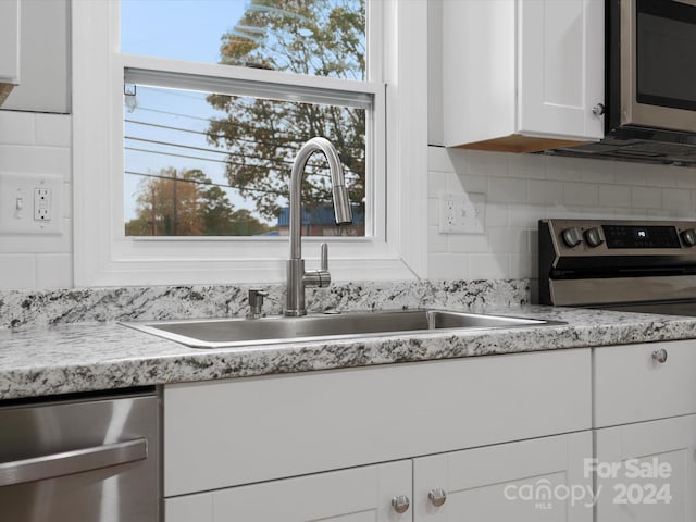 kitchen featuring appliances with stainless steel finishes, decorative backsplash, white cabinets, and sink