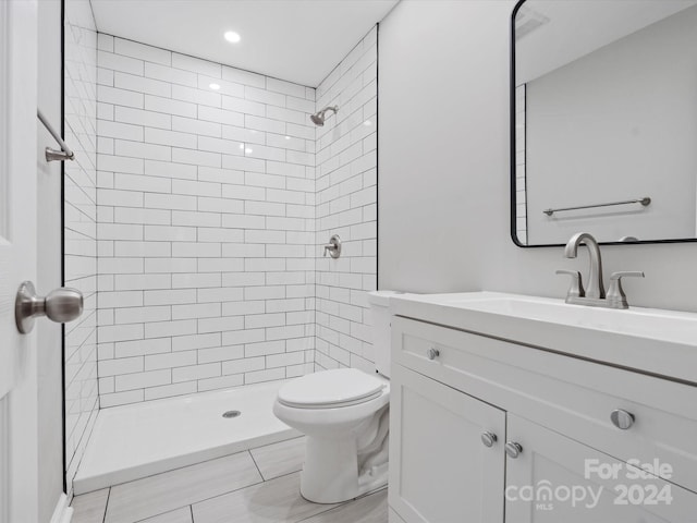 bathroom featuring vanity, tiled shower, and toilet