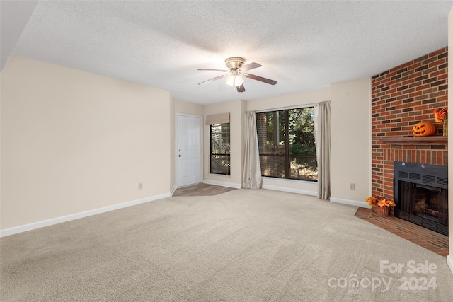 unfurnished living room with a textured ceiling, light carpet, a fireplace, and ceiling fan