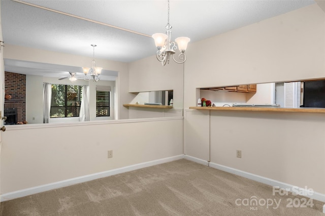 carpeted empty room featuring ceiling fan with notable chandelier and a brick fireplace