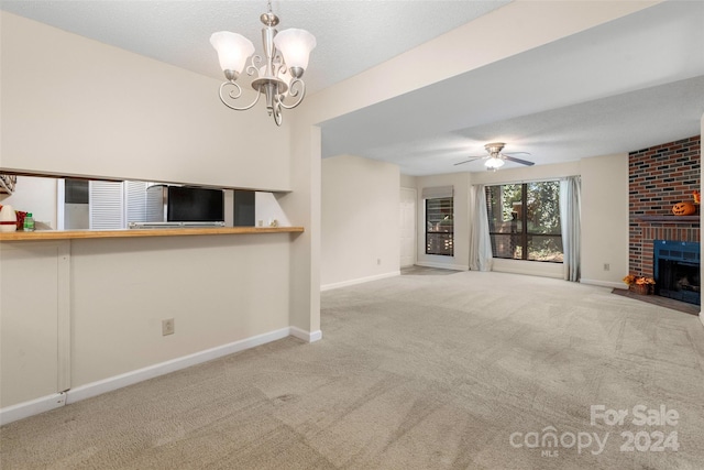 unfurnished living room featuring light carpet, a brick fireplace, and ceiling fan with notable chandelier