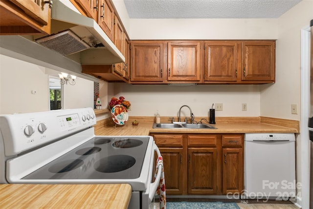 kitchen with a notable chandelier, a textured ceiling, sink, and white appliances