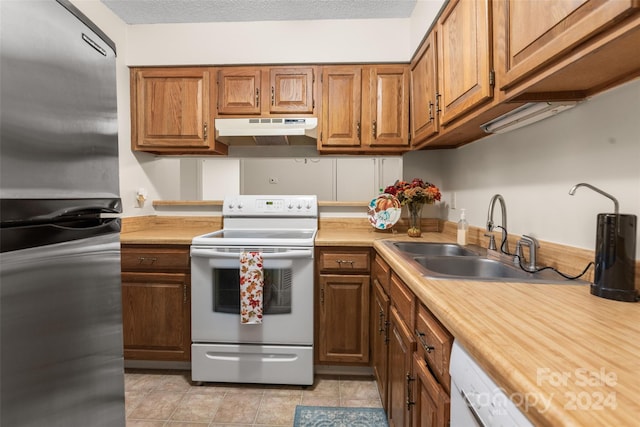 kitchen with a textured ceiling, sink, light tile patterned floors, and white appliances