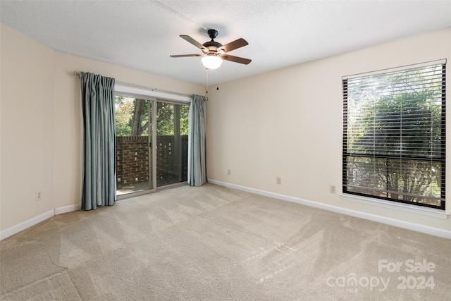 empty room with a textured ceiling, light colored carpet, and ceiling fan