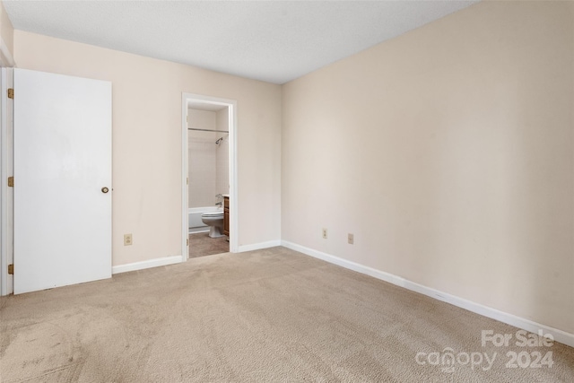 unfurnished bedroom with connected bathroom, a closet, carpet flooring, and a spacious closet