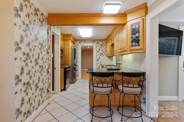 kitchen featuring stainless steel appliances, light tile patterned floors, kitchen peninsula, ornamental molding, and a kitchen breakfast bar