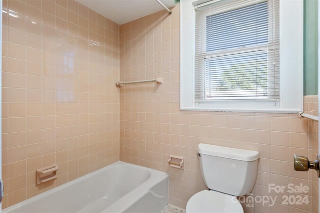 bathroom with tile walls, toilet, and tiled shower / bath