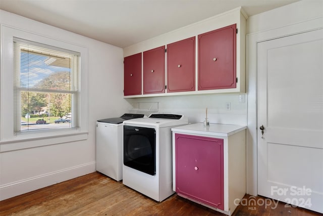 clothes washing area featuring washer and clothes dryer, light hardwood / wood-style floors, and cabinets