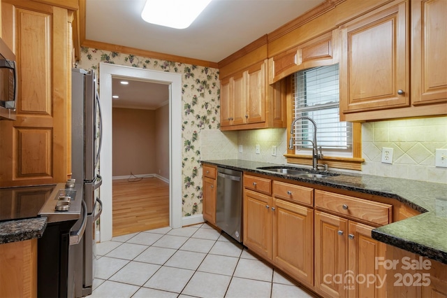 kitchen featuring light tile patterned floors, appliances with stainless steel finishes, ornamental molding, a sink, and wallpapered walls