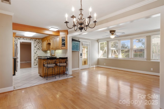 kitchen with dark countertops, ornamental molding, light wood-style floors, a kitchen bar, and wallpapered walls