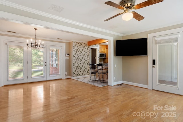 interior space with visible vents, baseboards, crown molding, light wood-style floors, and ceiling fan with notable chandelier