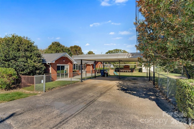 view of front of house with a carport, brick siding, fence, and driveway