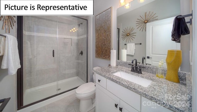 bathroom featuring tile patterned floors, toilet, a stall shower, and vanity