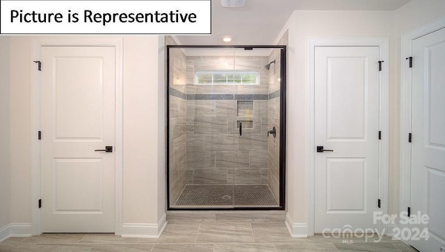 bathroom with a shower stall and baseboards