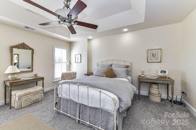 bedroom with a tray ceiling, dark carpet, and ceiling fan