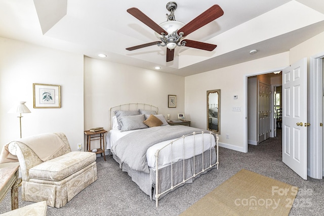 bedroom featuring dark colored carpet, ceiling fan, and a raised ceiling