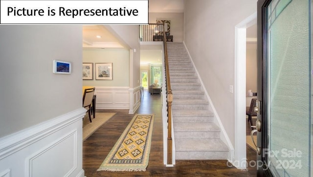 staircase featuring ornamental molding, a wainscoted wall, and wood finished floors
