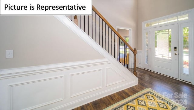 entryway with dark wood-style floors, a decorative wall, wainscoting, and stairway