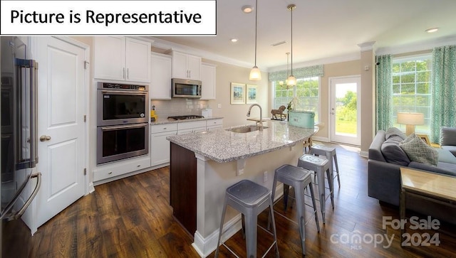 kitchen featuring dark wood-style flooring, light stone counters, crown molding, appliances with stainless steel finishes, and a sink