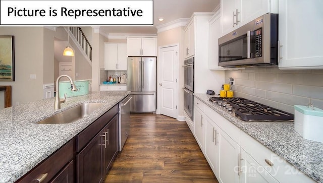 kitchen with a sink, ornamental molding, appliances with stainless steel finishes, dark brown cabinetry, and white cabinetry