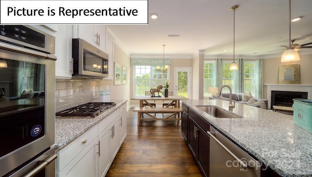 kitchen featuring a sink, dark wood-style floors, crown molding, stainless steel appliances, and light stone counters