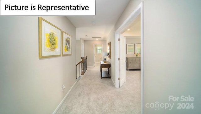 hallway with light carpet, an upstairs landing, visible vents, and baseboards