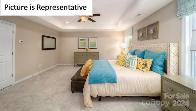 bedroom featuring a tray ceiling, carpet flooring, multiple windows, and visible vents
