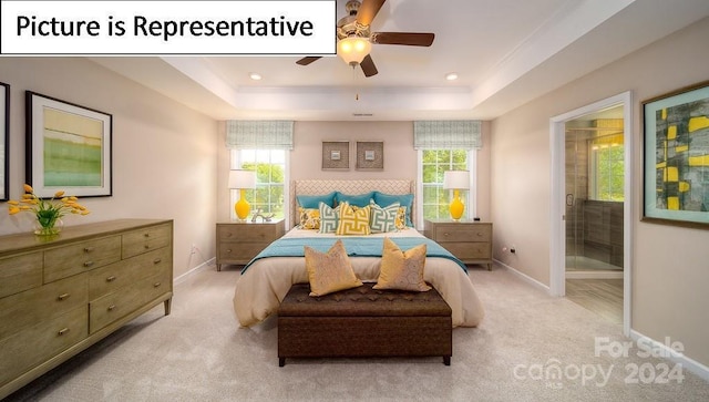 bedroom with ensuite bath, baseboards, light colored carpet, and a raised ceiling
