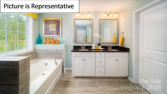 bathroom with a bath, double vanity, a sink, and baseboards
