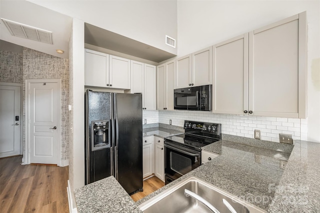 kitchen with backsplash, white cabinets, black appliances, and lofted ceiling