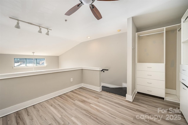 interior space with track lighting, vaulted ceiling, ceiling fan, light hardwood / wood-style floors, and a closet