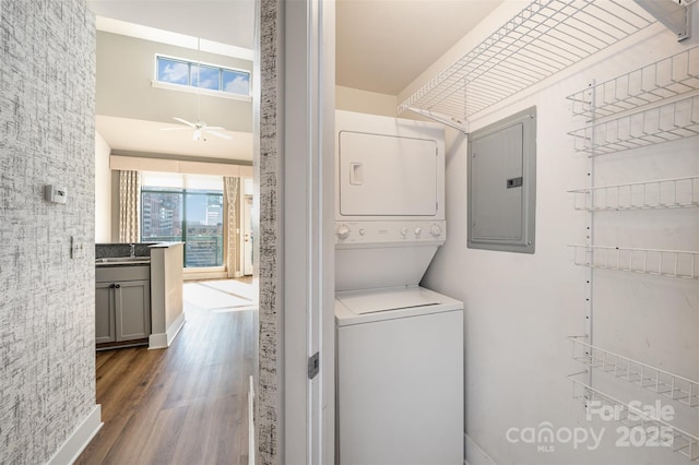 washroom with hardwood / wood-style floors, electric panel, sink, ceiling fan, and stacked washer / drying machine