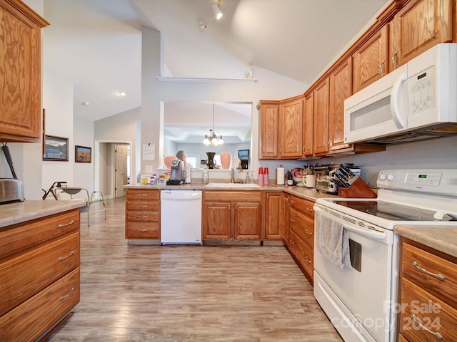 kitchen with white appliances, hanging light fixtures, lofted ceiling, light hardwood / wood-style flooring, and an inviting chandelier