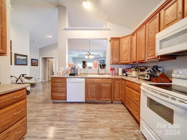 kitchen featuring light hardwood / wood-style flooring, hanging light fixtures, sink, an inviting chandelier, and white appliances