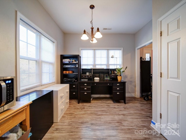 office area with a wealth of natural light, light hardwood / wood-style flooring, and an inviting chandelier