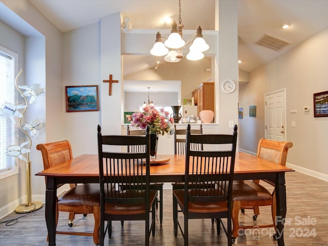 dining area featuring light hardwood / wood-style floors, a notable chandelier, and vaulted ceiling