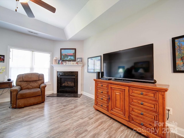 living room featuring a fireplace, light hardwood / wood-style floors, and ceiling fan