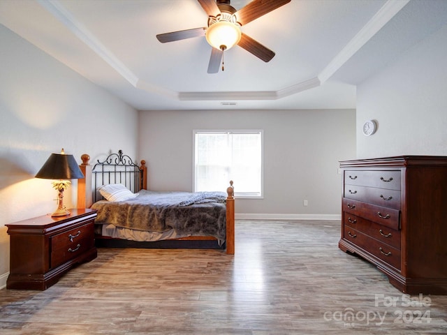 bedroom featuring light hardwood / wood-style flooring, a raised ceiling, and ceiling fan