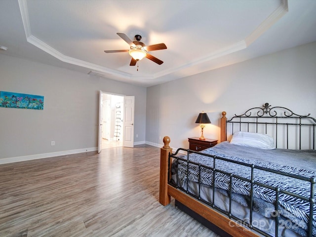 bedroom featuring ornamental molding, hardwood / wood-style flooring, a tray ceiling, and ceiling fan